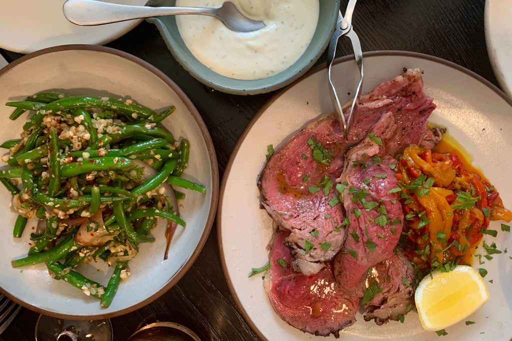 Plated harissa beef with green beans and a lemon wedge, showcased alongside a creamy sauce.