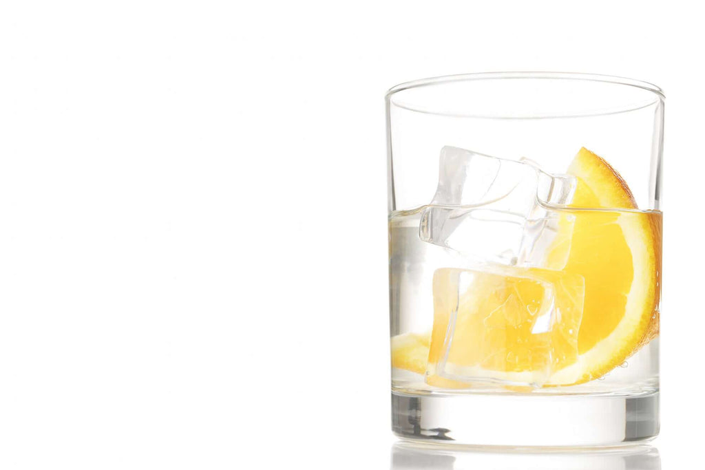 Refreshing vodka cocktail with ice and orange slices in a clear glass on a white background.