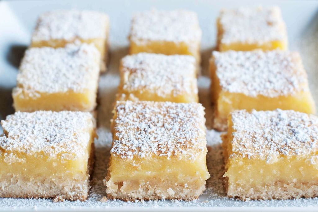 Delicious Meyer lemon bars dusted with powdered sugar on a white platter.