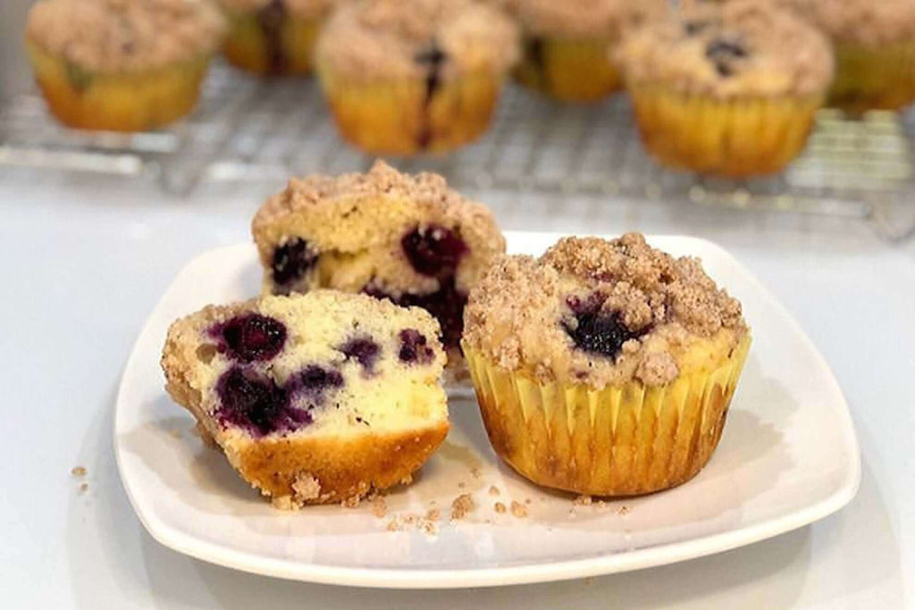 Delicious lemon blueberry muffins with crumb topping, showcased on a white plate, highlighting their soft texture and flavor.